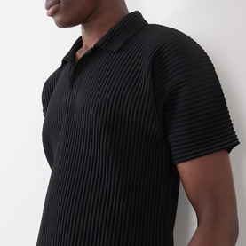 Model wearing Issey Miyake Open Collar Pleated Polo Shirt in black, featuring all-over pleating and open collar detail.