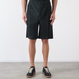 Model wearing Issey Miyake Special Black pinstripe shorts with elasticated waist, styled with navy lace-up trainers.