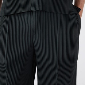 Model wearing Issey Miyake Special Black pleated polyester shorts, close-up showing textured ribbed detail at waist and leg.