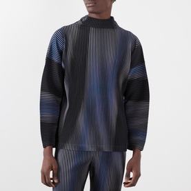Model wearing Issey Miyake Gradient Pleated T-Shirt in blue, with high neck, long sleeves, and abstract striped pleated design. Styled with matching