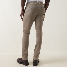 Model wearing Jacob Cohen Bobby Slim Leg Chinos in Elephant Grey, rear view showing slim cut, rear pockets and leather logo patch, styled with brown