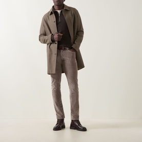 Model wearing Jacob Cohen 3049 Elephant Grey cord jeans styled with a taupe overcoat, dark knit and brown leather shoes.