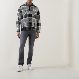 Model wearing Jacob Cohen 3049 slim jeans in medium black, styled with a black and white check overshirt and white trainers.