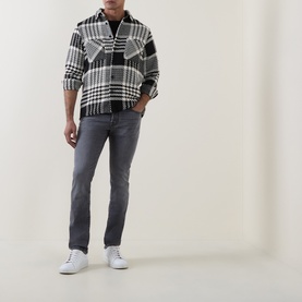 Model wearing Jacob Cohen 3049 slim jeans in medium black, styled with black-and-white check overshirt and white trainers.
