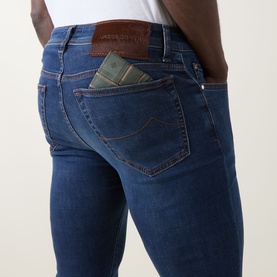 Model wearing Jacob Cohen Bard Slim Leg Jeans in medium blue, rear view showing leather logo patch and handkerchief detail in back pocket