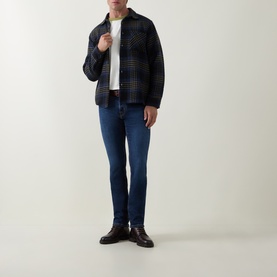 Model wearing Jacob Cohen 3049 slim jeans in dark blue, styled with a check overshirt, white tee and brown leather shoes.