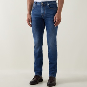 Model wearing Jacob Cohen 3049 slim jeans in dark blue denim with subtle fading, styled with dark brown leather shoes.
