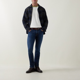Model wearing Jacob Cohen 3049 slim jeans in dark blue, styled with a checked overshirt, white tee, and black leather shoes.