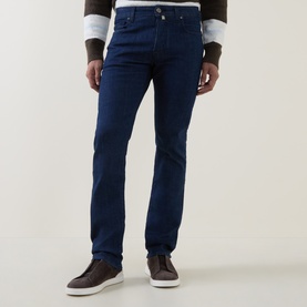 Model wearing dark blue slim-fit jeans, styled with a grey striped long-sleeve top and brown leather loafers