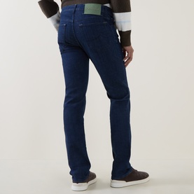 Model wearing dark blue slim-fit jeans with green back tab, styled with a two-tone jacket and brown leather shoes