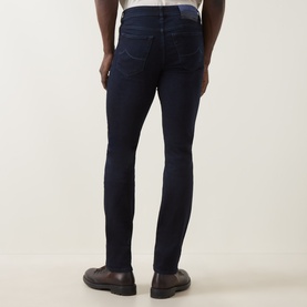 Model wearing Jacob Cohen 3049 slim jeans in dark blue, rear view, styled with dark brown leather shoes.