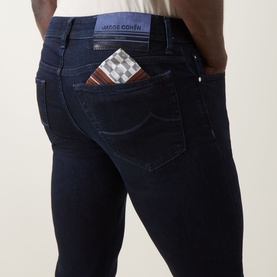 Model wearing Jacob Cohen 3049 slim jeans in dark blue, rear view showing back pockets with branded patch detail.