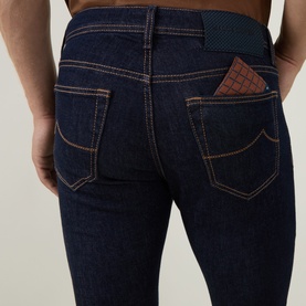 Model wearing Jacob Cohen 3049 slim jeans in dark blue denim, rear view showing contrast stitching and brown crocodile-embossed wallet in pocket.