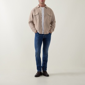 Model wearing Jacob Cohen 3049 slim jeans in light blue, styled with a beige overshirt, white tee and black leather shoes.