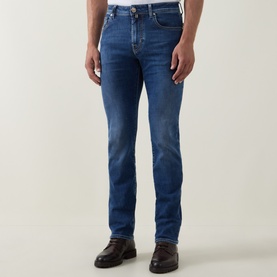 Model wearing Jacob Cohen 3049 slim jeans in light blue with faded wash detail, styled with dark brown leather shoes.