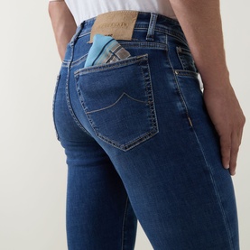 Model wearing Jacob Cohen 3049 slim jeans in light blue denim, rear view showing branded pocket detail with signature suede patch.