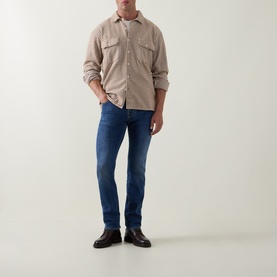 Model wearing Jacob Cohen 3049 Slim Jeans in 300D Light Blue, styled with a beige overshirt and dark leather loafers.