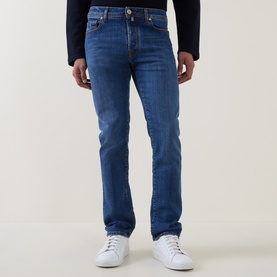 Model wearing Jacob Cohen 3049 slim jeans in medium blue denim, styled with white trainers and a navy top