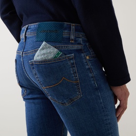 Model wearing Jacob Cohen 3049 Slim Jeans in medium blue denim, rear view showing signature patch and pocket square detail.