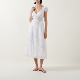 Model wearing LOVESHACKFANCY Suvi Lace Trim Flared Dress in white, midi length with V-neckline, cap sleeves and lace trim detail. Styled with flat