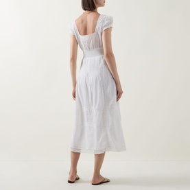 Model wearing LOVESHACKFANCY Suvi Lace Trim Flared Dress in white, midi length with cap sleeves, empire waist and A-line silhouette, back view