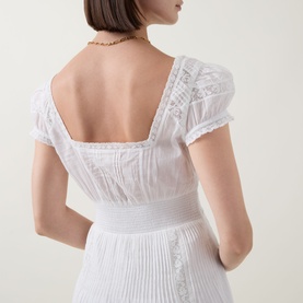 Model wearing LOVESHACKFANCY Suvi Lace Trim Flared Dress in white, showing square back neckline, lace trim, cap sleeves and back smocking detail