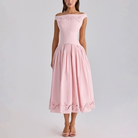 Model wearing House of CB pink off-shoulder midi dress with floral cutwork hem detail and full pleated skirt, styled with nude heels