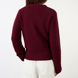Model wearing Lisa Yang Deep Plum cashmere cardigan, back view, styled with white wide-leg trousers