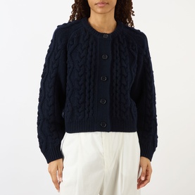 Model wearing Lisa Yang navy cashmere cable-knit cardigan with button front, styled with white wide-leg trousers.