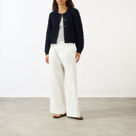 Model wearing Lisa Yang navy cashmere cardigan with textured knit detail, styled with white wide-leg trousers and flat sandals.