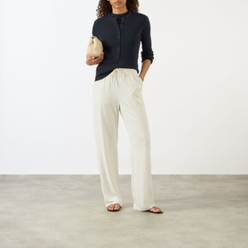 Model wearing Lisa Yang Airi Navy Cashmere Polo Shirt with cream wide-leg trousers and tan sandals, carrying a small cream bag.