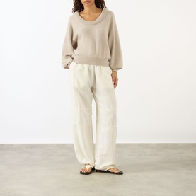 Model wearing Lisa Yang The Doria Cashmere Sweater in Sand with scoop neck, styled with cream wide-leg trousers and dark flat sandals.