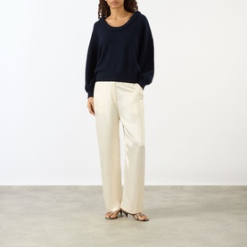 Model wearing Lisa Yang The Doria Cashmere Sweater in navy with scoop neckline, styled with cream wide-leg trousers and strappy sandals