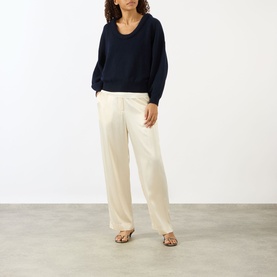 Model wearing Lisa Yang The Doria Cashmere Sweater in navy with scoop neckline, styled with cream wide-leg trousers and leopard print sandals.