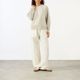 Model wearing Lisa Yang The Hally Cashmere Sweater in Oyster, crew neck with ribbed trims, styled with cream wide-leg trousers and sandals.