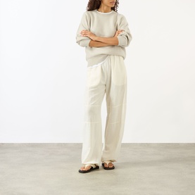 Model wearing Lisa Yang The Hally Cashmere Sweater in Oyster, crew neck, long sleeves, styled with wide-leg cream trousers and brown sandals