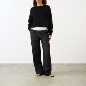 Model wearing Lisa Yang The Karine Sweater in black with wide-leg trousers and flat sandals