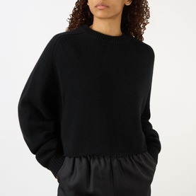 Model wearing Lisa Yang The Karine Sweater in black cashmere with crew neck, dropped shoulders, and ribbed trims, styled with black satin skirt.