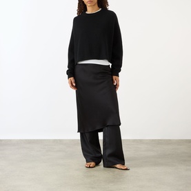 Model wearing Lisa Yang The Karine Sweater in black, cropped cashmere knit with dropped shoulders, styled with black midi skirt and wide-leg trousers