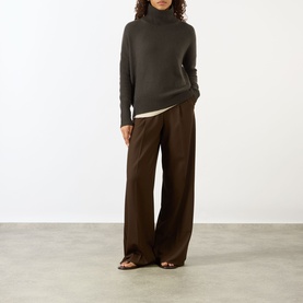 Model wearing Lisa Yang The Heidi Turtleneck Sweater in Dove Grey, 100% cashmere, with wide-leg brown trousers and brown sandals.