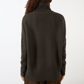 Model wearing Lisa Yang The Heidi Turtleneck Sweater in Dove Grey, back view, showing dropped shoulders and ribbed hem