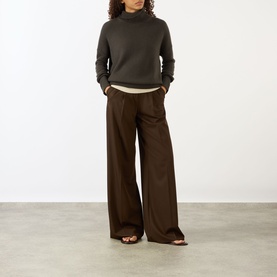 Model wearing Lisa Yang The Heidi Turtleneck Sweater in Dove Grey, styled with wide-leg brown trousers and brown sandals.