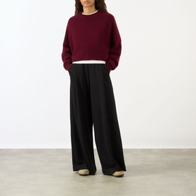 Model wearing Lisa Yang The Karine Sweater in Deep Plum, cropped cashmere knit with crew neck, styled with wide-leg black trousers.
