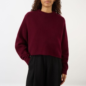 Model wearing Lisa Yang The Karine Sweater in Deep Plum, cropped cashmere knit with crew neck and dropped shoulders, styled with black wide-leg