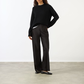Model wearing Lisa Yang black cashmere knit sweater with wide-leg trousers and black flat shoes