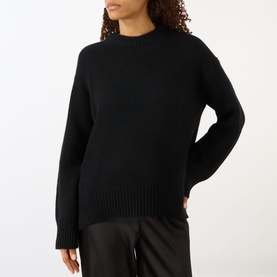 Model wearing Lisa Yang black cashmere knit jumper with mock neck and ribbed hem, styled with black satin trousers