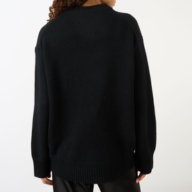 Model wearing Lisa Yang black cashmere knit jumper, shown from behind with relaxed oversized fit and ribbed hem detail.
