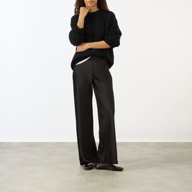 Model wearing Lisa Yang black cashmere knit sweater with wide-leg black trousers and black ballet flats.