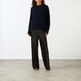 Model wearing Lisa Yang Noor Cashmere Sweater in navy with ribbed trims and crew neck, styled with wide-leg black trousers.