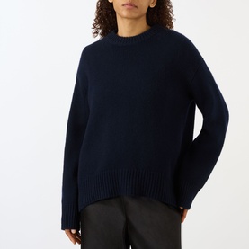 Model wearing Lisa Yang Noor Cashmere Sweater in navy with ribbed trims and crew neckline, styled with dark trousers.
